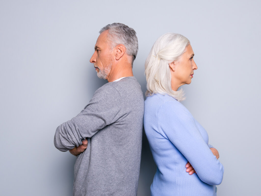 older man and woman standing back to back during gray divorce