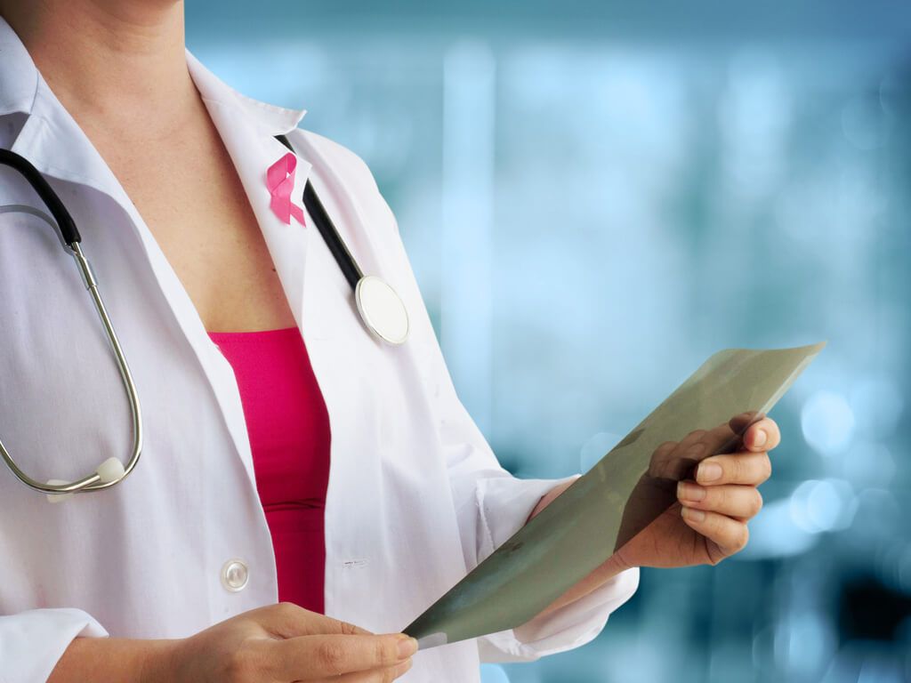 female doctor reviewing a file while wearing a breast cancer awareness pin